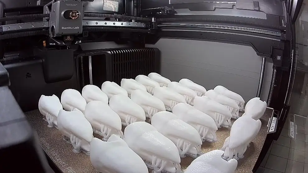 Impressora 3D produzindo diversas peças anatômicas brancas em série