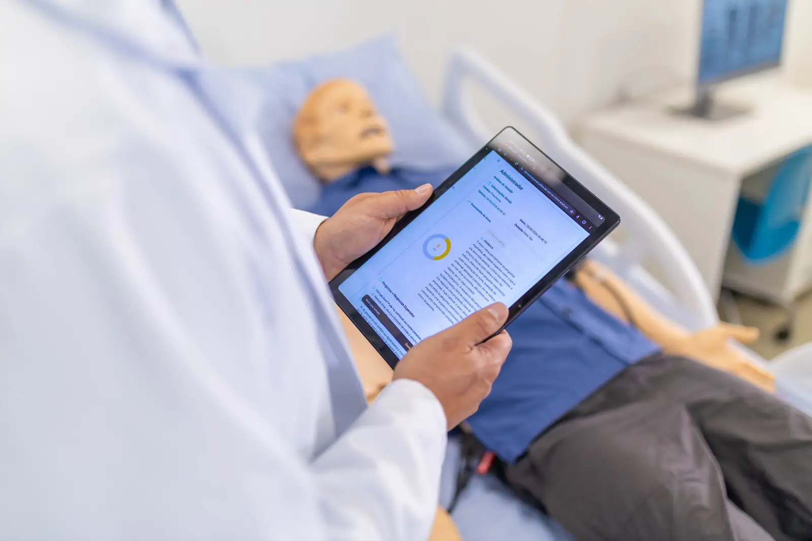 Professor consulta tablet com dados de simulação ao lado de manequim de alta fidelidade
